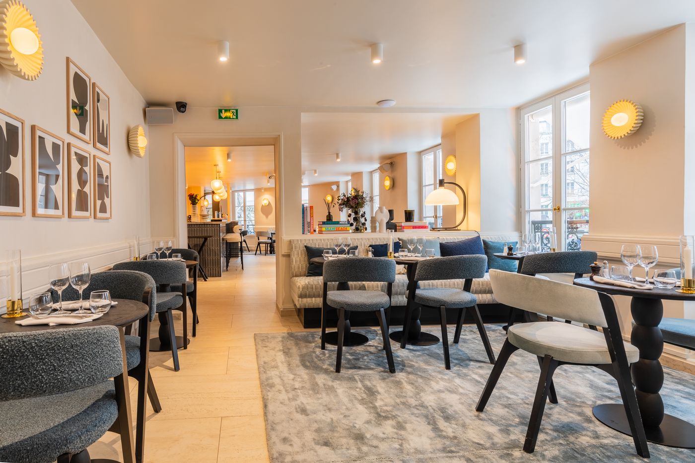 Salle aux estampes encadrées, tapis bleu et fauteuils en bouclette