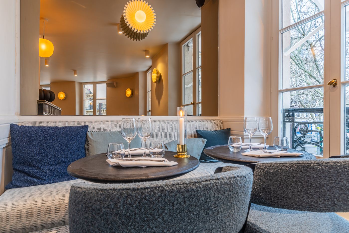 Table dressée avec bougie près d'une grande fenêtre donnant sur l'avenue